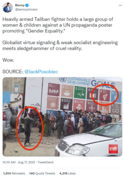 全副武装的塔利班战士持枪对着一大群妇女和儿童，对抗联合国宣传&lsquo;性别平等&rsquo;的海报